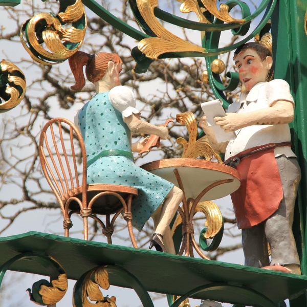Illustration représentant deux figurines : une dame assise à une table de restaurant et un serveur