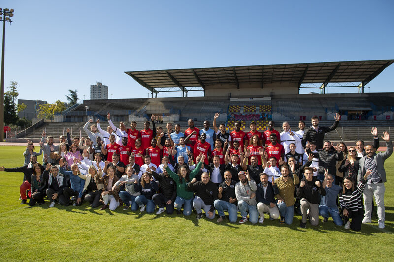 Photo d'un groupe d'une 50aine de personnes devant les tribunes d'un stade